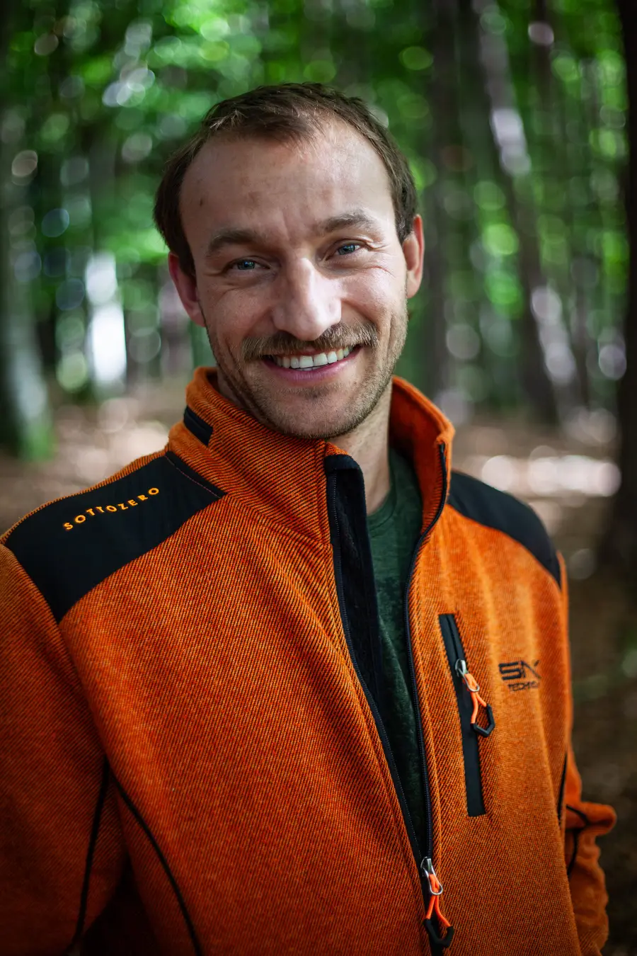 Porträt von Michael Stellbauer, Inhaber von Stellpower, in oranger Arbeitsjacke im Wald